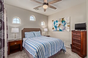 A bedroom with a bed, nightstands, a dresser, a ceiling fan, and a painting on the wall. - Heated pool, jacuzzi, Fast Wifi, Pac Man, Fire Pit, BBQ, Sleeps 14! (Phoenix)