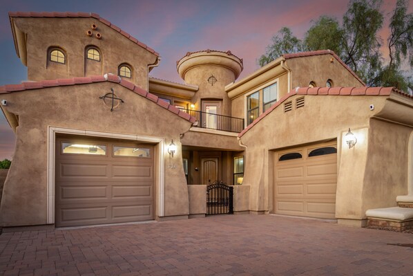A stucco house with two garage doors, a balcony, and a circular tower. - Heated pool, jacuzzi, Fast Wifi, Pac Man, Fire Pit, BBQ, Sleeps 14! (Phoenix)