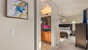 A spacious bedroom with a large bed, a nightstand, and a dresser. There is a kitchen area with wooden cabinets and a countertop. - Heated pool, jacuzzi, Fast Wifi, Pac Man, Fire Pit, BBQ, Sleeps 14! (Phoenix)