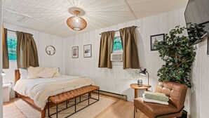 A bedroom with a bed, a bench, a chair, a small table, a plant, and a ceiling fan. - Outdoor Theatre | Hot Tub | Fire Pit | Dogs (Luray)