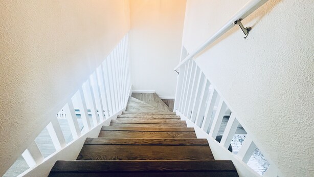 Eine Holztreppe mit weißen Geländern und einer hängenden Leuchte.