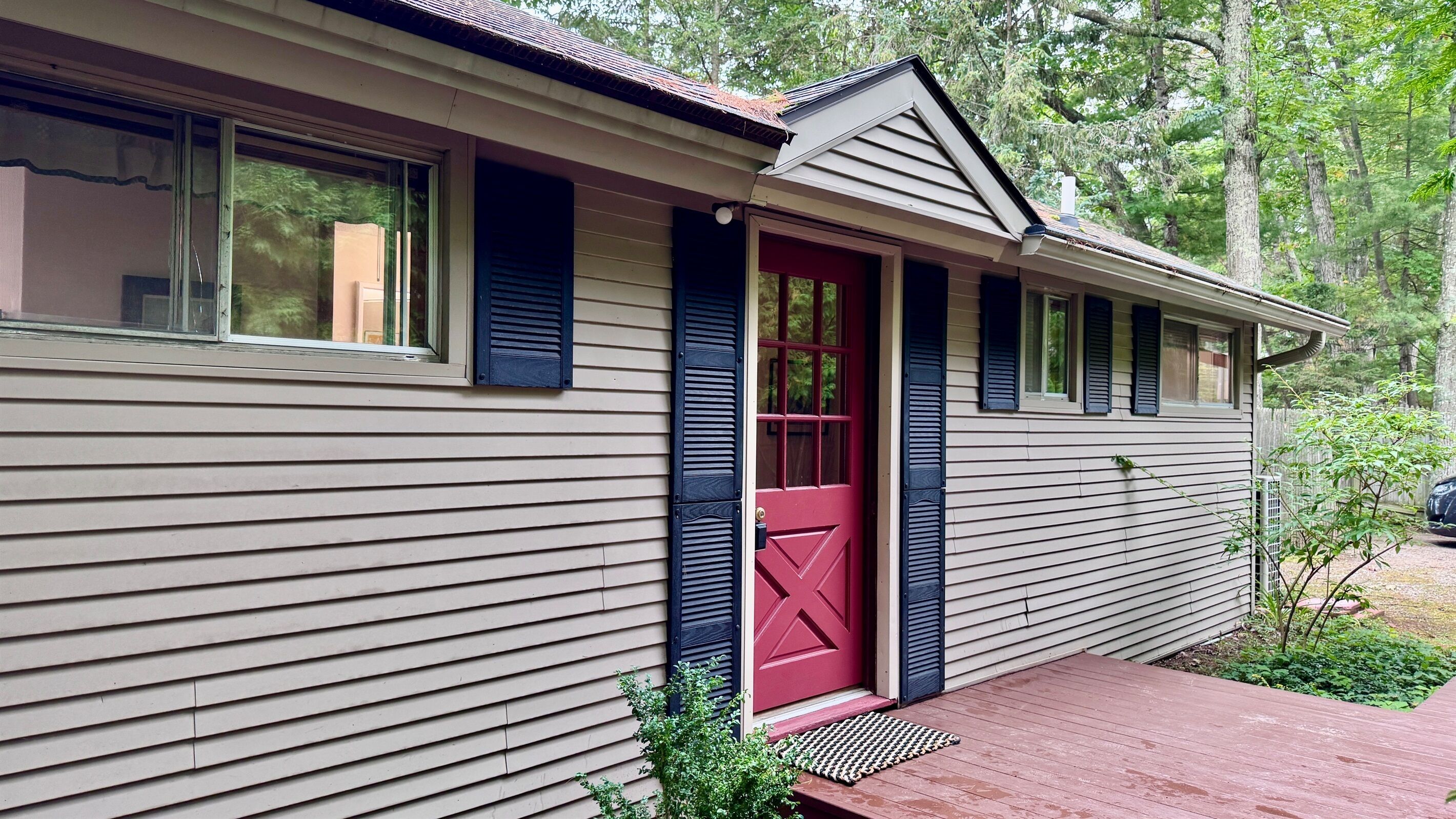 A house with a red door, a covered porch, and a small garden area.