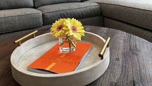 Una sala de estar con una mesa redonda, un libro titulado 'Chattanooga', un florero con flores, un cojín rojo con la frase 'vive, ríe, ama' y un cartel de Chattanooga en la pared.