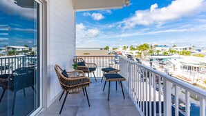A balcony with wicker chairs and a table, overlooking a marina with boats and palm trees. - Waterfront, 4Br/3B Home, 5 min from John Pennekamp State Park (Key Largo)