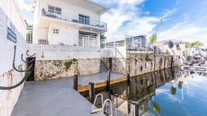 A white building with balconies, a dock, and a clear sky. - Waterfront, 4Br/3B Home, 5 min from John Pennekamp State Park (Key Largo)