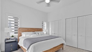 A bedroom with a wooden bed, white walls, a ceiling fan, and a wardrobe. - Waterfront, 4Br/3B Home, 5 min from John Pennekamp State Park (Key Largo)