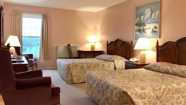 A hotel room with two beds, a chair, a desk, and a painting on the wall. - Rollo Bay Inn (Rollo Bay)