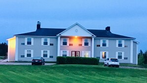 A two-story house with a front entrance, a driveway, and two cars parked in the driveway. - Rollo Bay Inn (Rollo Bay)