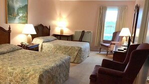 A hotel room with two beds, a sitting area with a chair, a table, and a lamp. - Rollo Bay Inn (Rollo Bay)