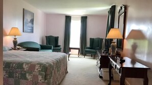 A hotel room with a large bed, two armchairs, a desk, and a dresser. - Rollo Bay Inn (Rollo Bay)