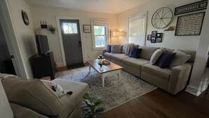 A living room with a sofa, a coffee table, a television, and a door.