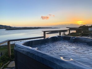 A hot tub with a view of the sunset over a body of water. - River’s End-Best Pacific Ocean and Rogue River Views on 2+Acres with a Hot Tub!  (Gold Beach)