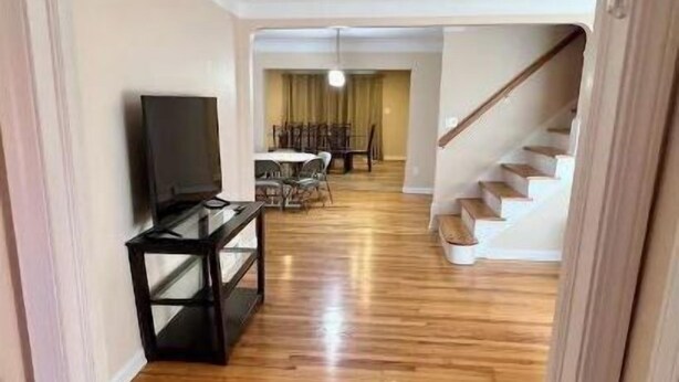 A hallway with wooden flooring leading to a dining area with a table and chairs, and a staircase. - Beautifully Renovated, Luxury Home in Beachwood OH (Beachwood)