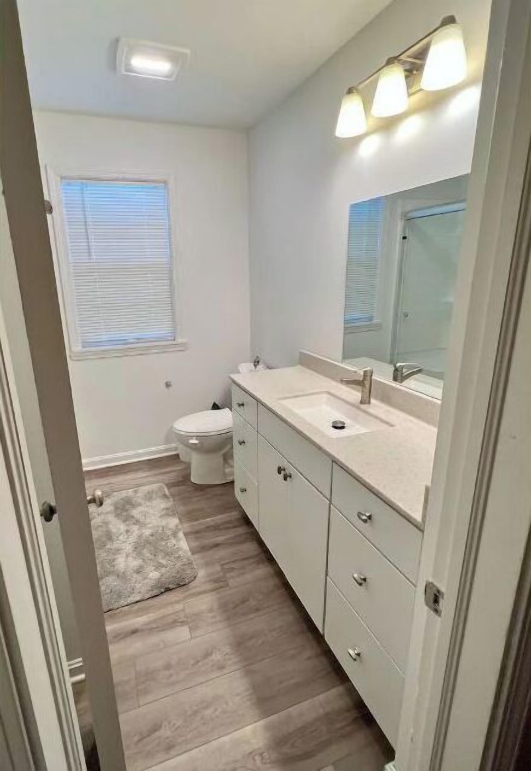 Un baño con tocador blanco, un espejo y un inodoro.