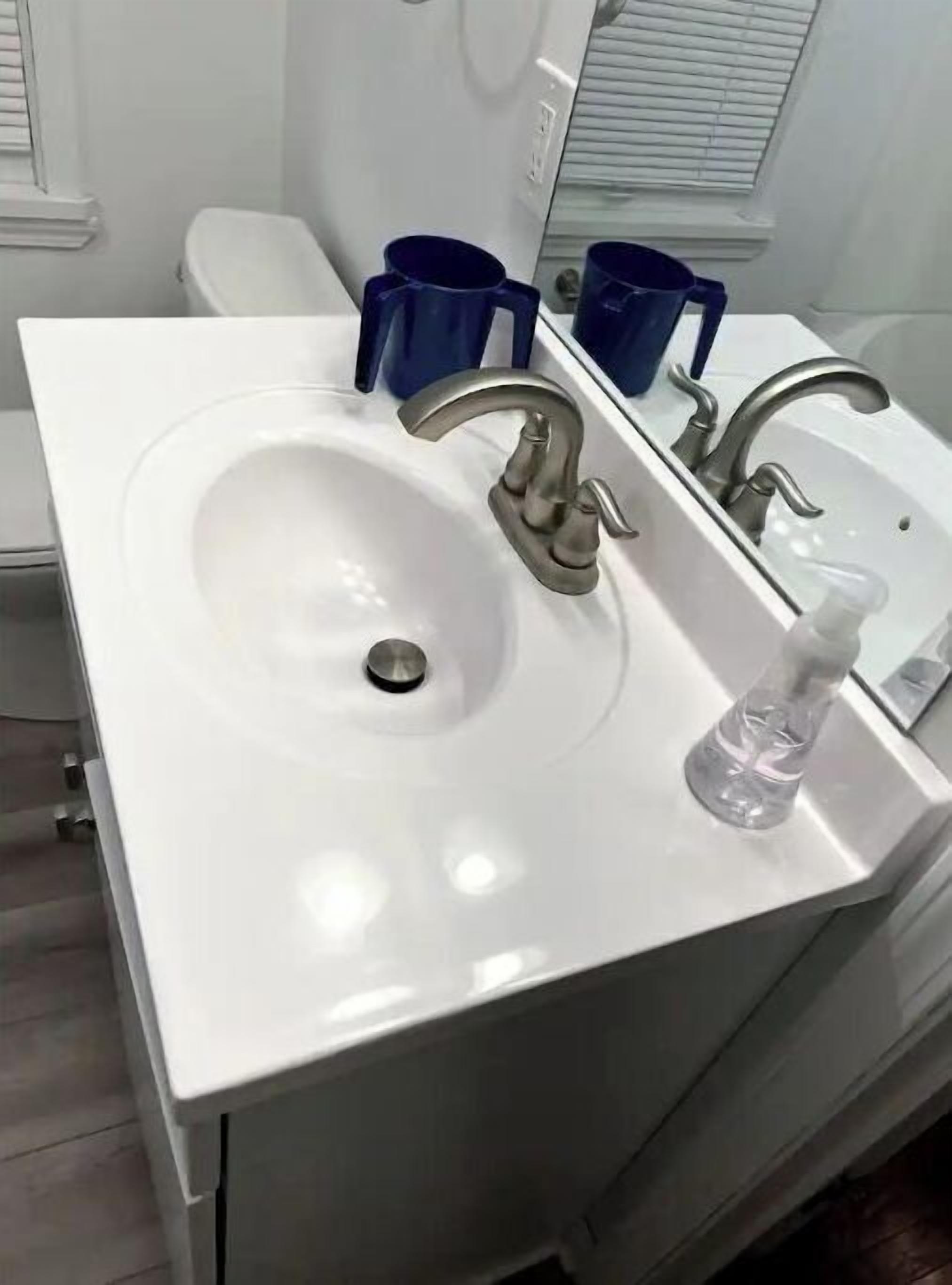 A bathroom with a white sink, two faucets, and a mirror.