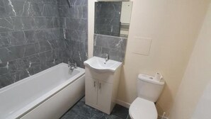 A bathroom with a bathtub, sink, and toilet. - 4 Bed House Sleeps 12 - Private Garden - Parking (London)