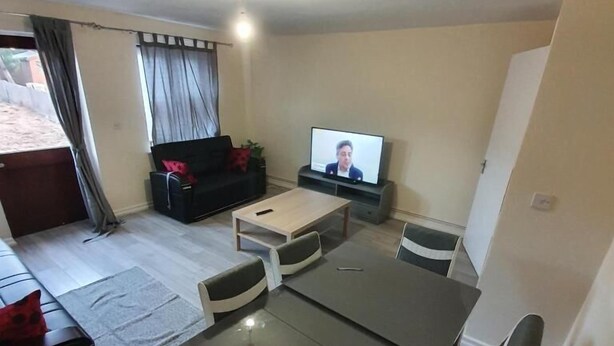 A living room with a sofa, TV, dining table, and chairs. - 4 Bed House Sleeps 12 - Private Garden - Parking (London)
