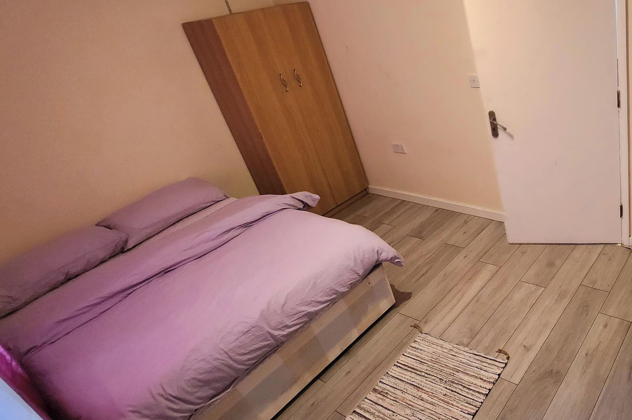 Ein Schlafzimmer mit einem Bett, einem Holzschrank und einer Tür.