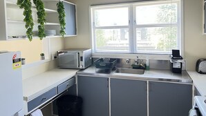 Eine kleine Küche mit einer Mikrowelle, einem Spülbecken und einem Fenster mit Jalousien.