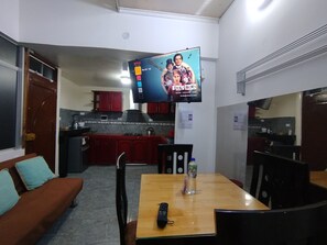 A compact living space with a kitchenette, a dining area with a table and chairs, and a television mounted on the wall. - Departamentos Appart d'Eliette (Trujillo)