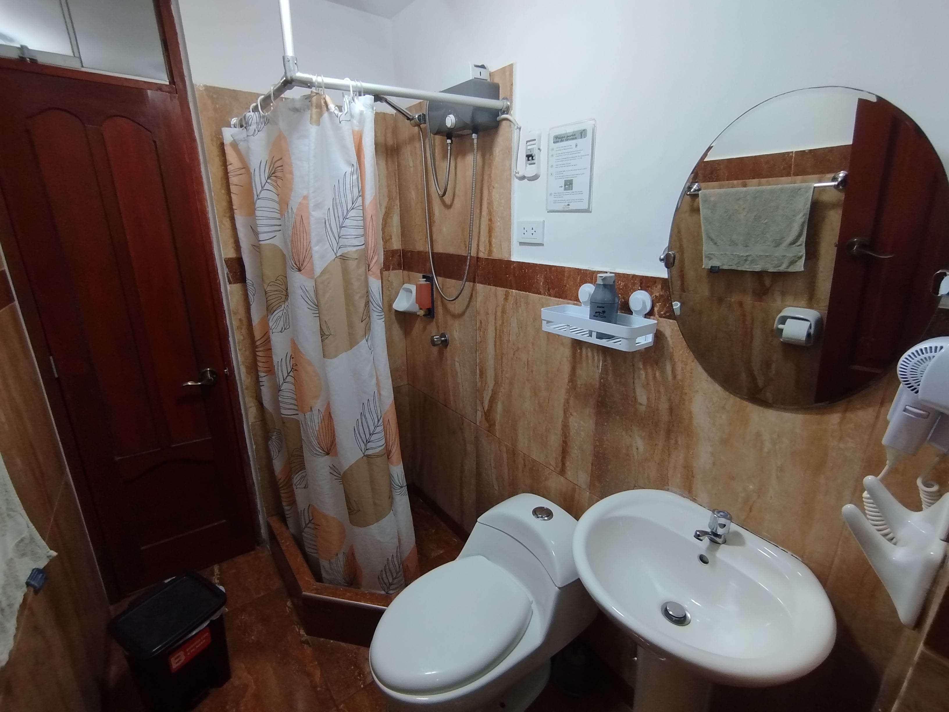 Een badkamer met twee toiletten, een wastafel, een douchegordijn, een handdoekrek en een spiegel.