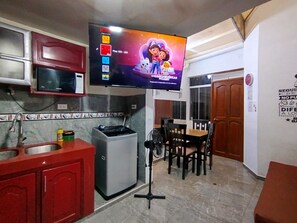 Cozinha compacta com micro-ondas, mini geladeira e espaço de refeições com cadeiras e mesa.