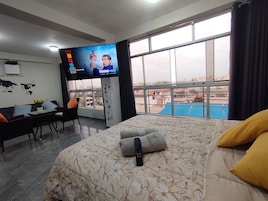 Una habitación de hotel con cama, escritorio, televisión y vistas de la ciudad.