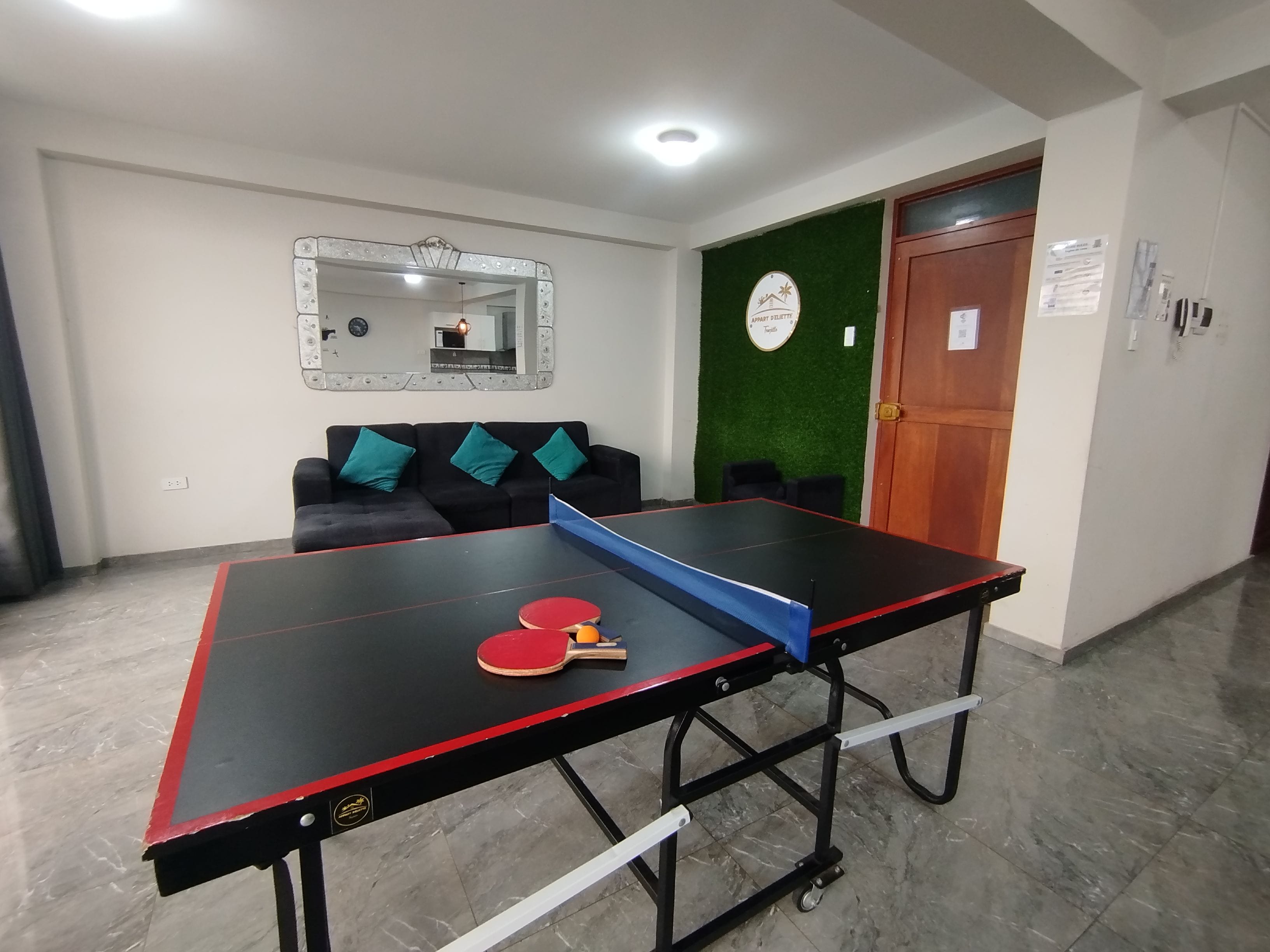 A ping pong table with paddles in a room with a sofa and a mirror on the wall.