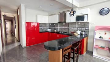 Una cocina moderna con una isla roja, encimera negra y taburetes de madera.