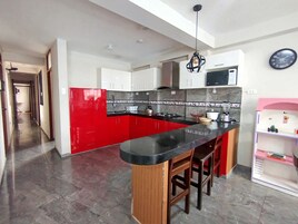 Una cocina moderna con una isla roja, encimera negra y taburetes de madera.