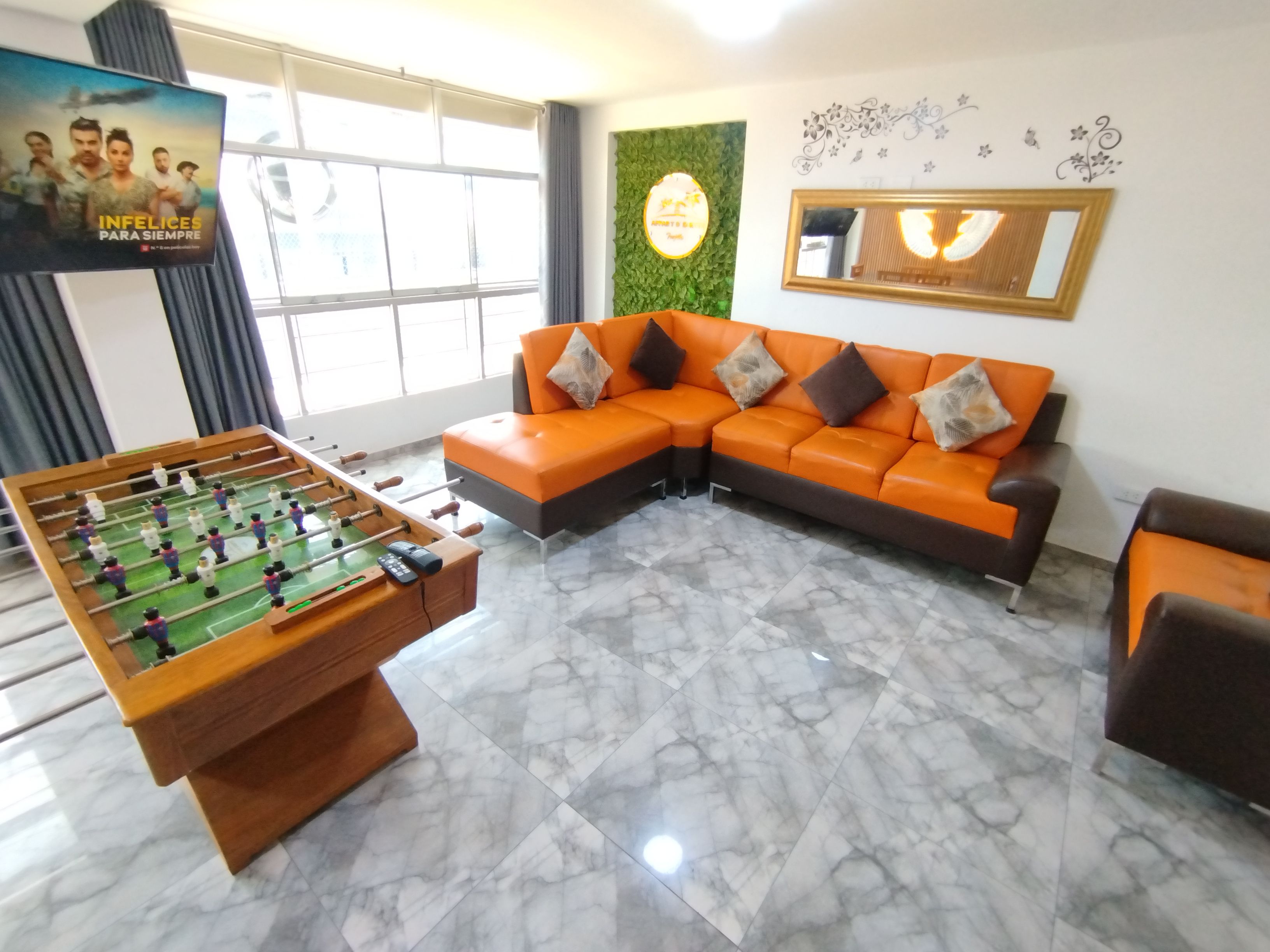 A living room with a foosball table, a sectional sofa, and a television.