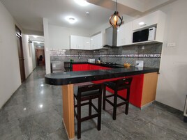 Una cocina moderna con una isla de encimera negra, armarios rojos y una campana extractora de acero inoxidable.
