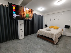 Un dormitorio con una cama, un televisor montado en la pared, una cortina y una pared decorada con notas musicales.