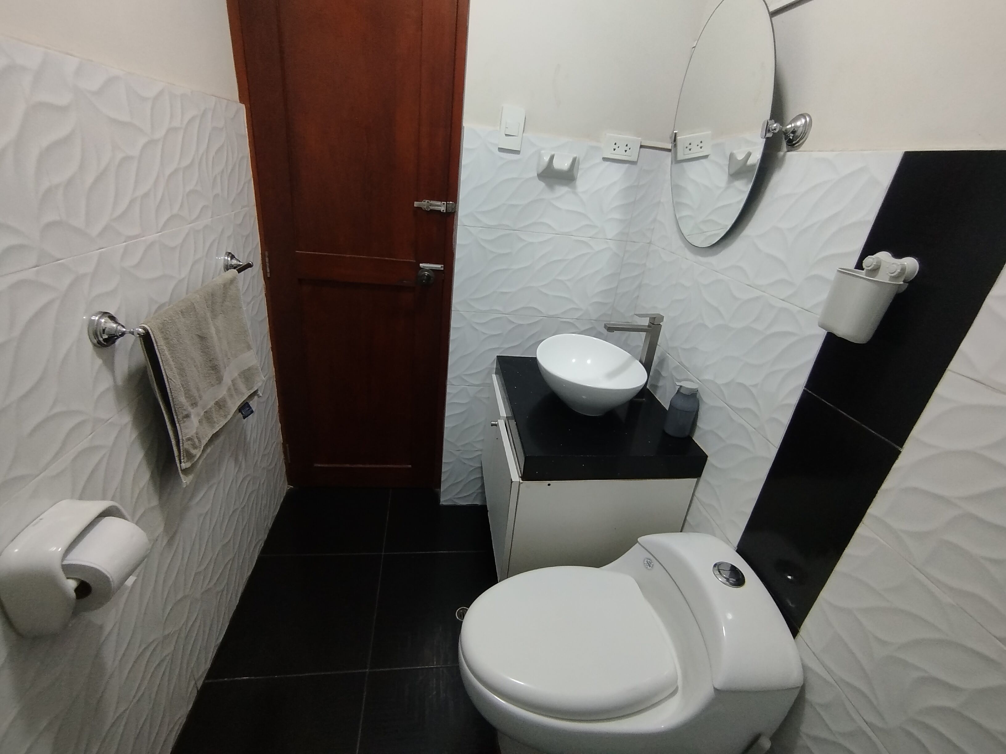 Une petite salle de bain comprenant des toilettes, un lavabo et un porte-serviettes.