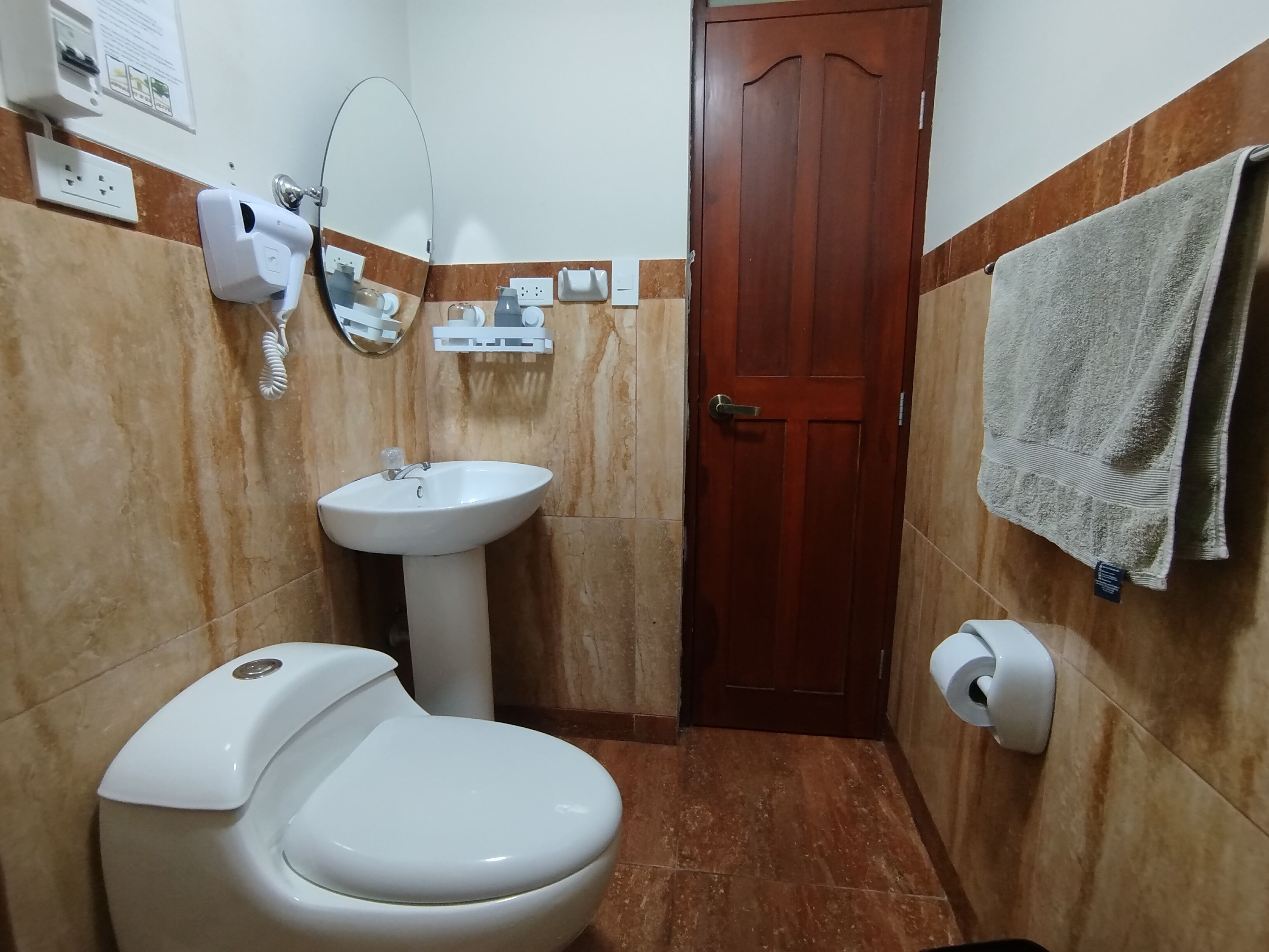 A bathroom with a toilet, sink, mirror, and towel rack.