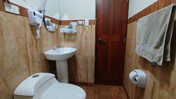 A bathroom with a toilet, sink, mirror, and towel rack.
