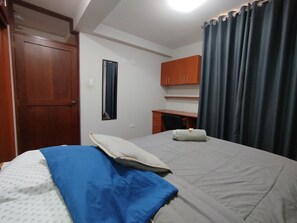 A bedroom with a bed, a desk, a mirror, and a wardrobe. - Departamentos Appart d'Eliette (Trujillo)