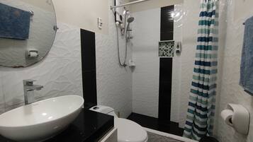 Un baño con un lavamanos blanco, un inodoro, una ducha con cortina a rayas y un espejo en la pared.