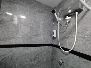 Un baño moderno con ducha, paredes de mármol y una franja decorativa negra.