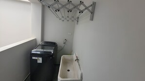 A laundry area with a washing machine, a drying rack, and a sink. - Departamentos Appart d'Eliette (Trujillo)