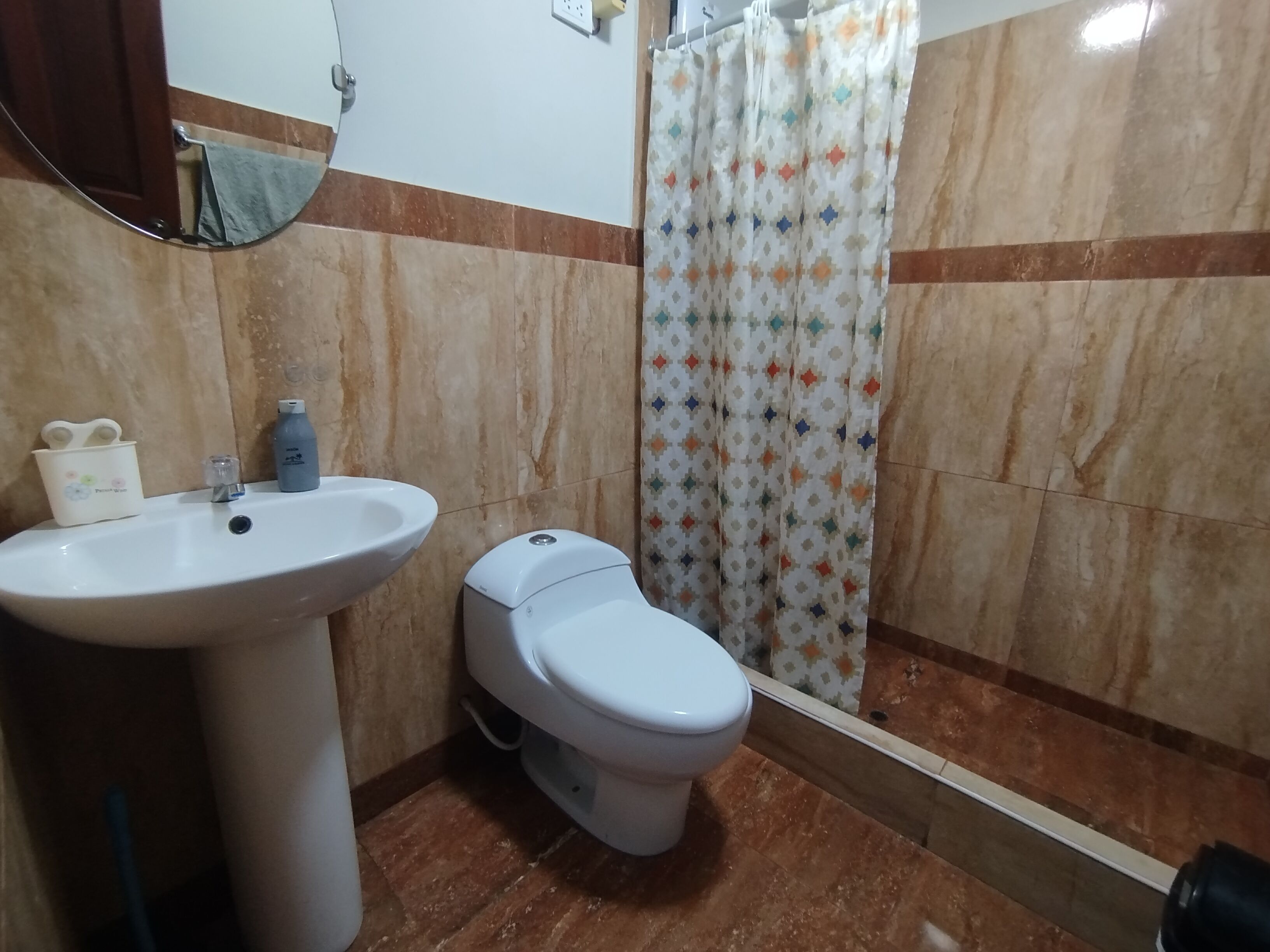 Un baño con lavamanos, inodoro y cortina de ducha.