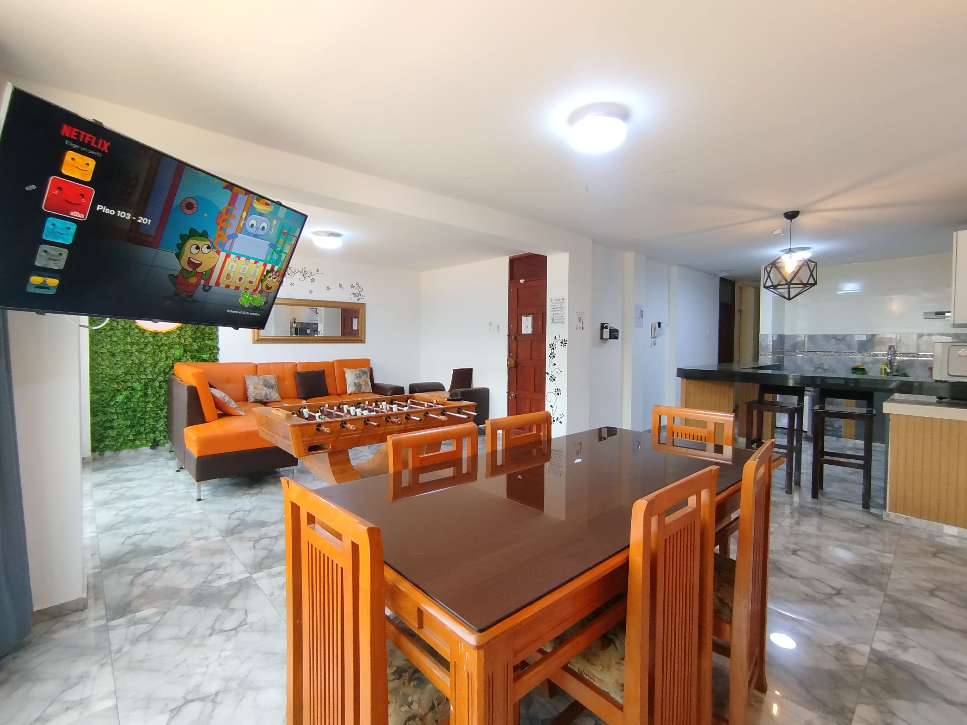 Una sala de estar moderna con una mesa de fútbol, un sofá y un televisor que muestra una caricatura.