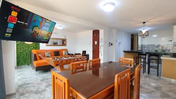 Una sala de estar moderna con una mesa de fútbol, un sofá y un televisor que muestra una caricatura.