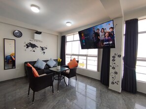 Una sala de estar moderna con un sofá, sillas, una mesa de centro, un televisor de pantalla plana, un mural de un mapa mundial y una ventana con cortinas.