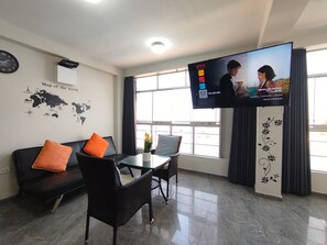 Una sala de estar moderna con un sofá, sillones, una mesa de centro, un televisor de pantalla plana, una decoración de mapa mundial en la pared y un ventanal grande.