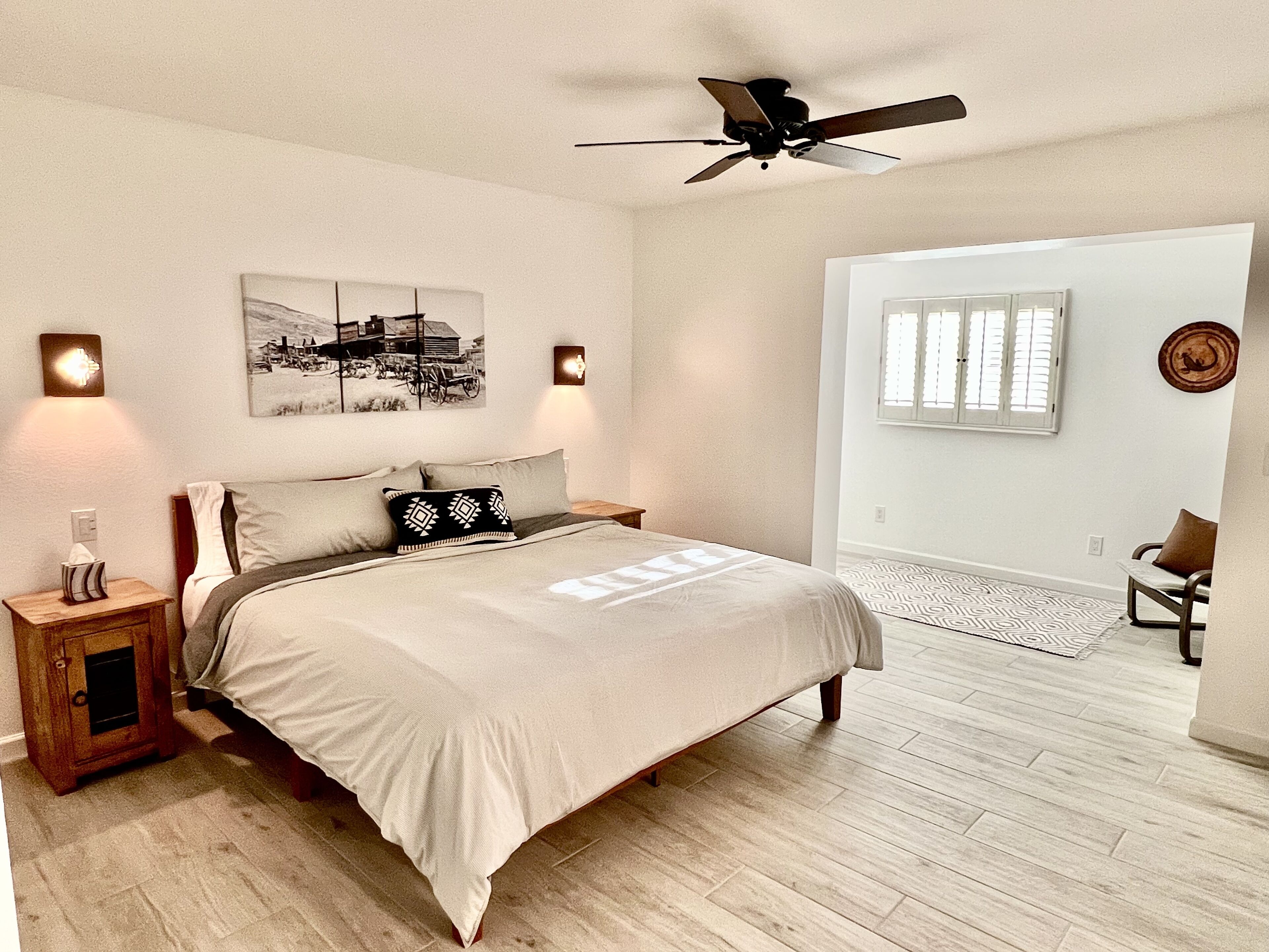 A bedroom with a bed, bedside lamps, a ceiling fan, a rug, and a chair.