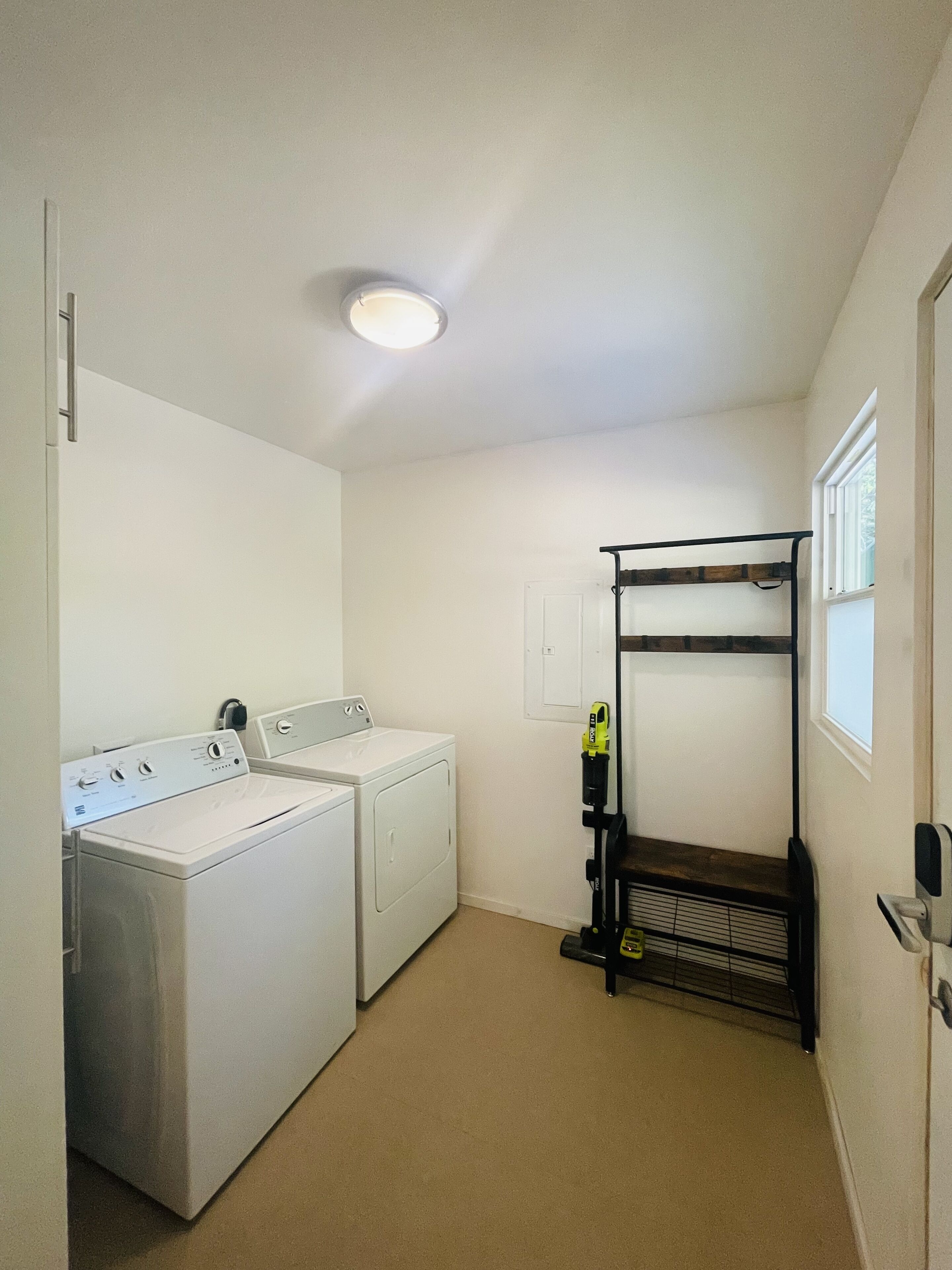 A laundry room with a washing machine, dryer, and a metal drying rack.