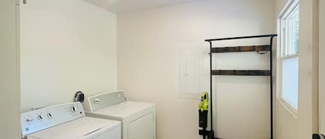 A laundry room with a washing machine, dryer, and a metal drying rack.