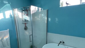 Un baño con cabina de ducha de vidrio, una bañera blanca y una pared azul.