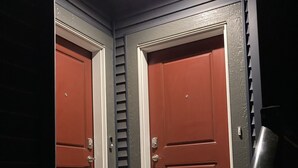 En hall med två röda dörrar och en metallstege som står lutad mot väggen.